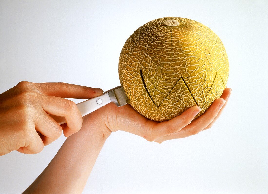 Cutting a galia melon in half with a zigzag edge