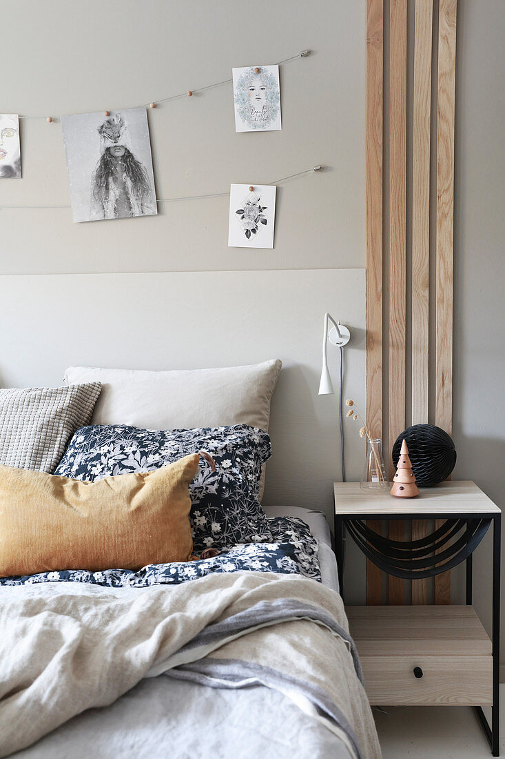 Bilder über Doppelbett und Holzlatten vor Nachttisch im Schlafzimmer