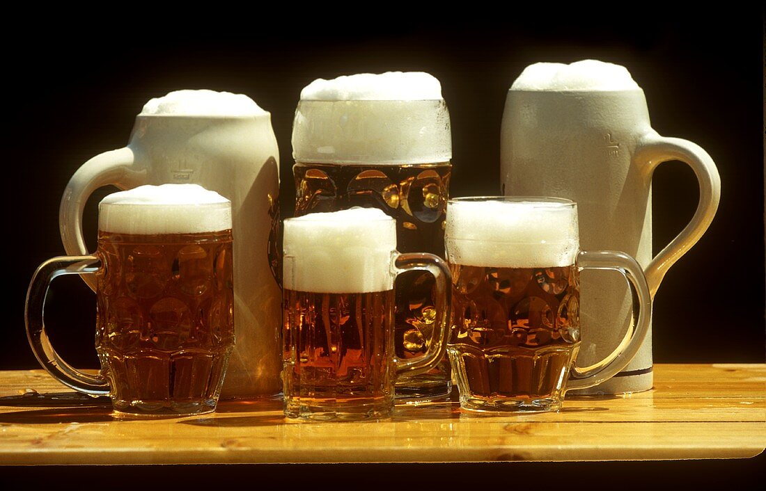 Various full beer tankards on a pub table