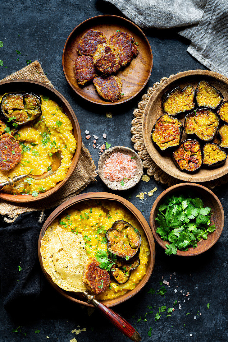 Bengali Khichdi serviert mit Auberginen, Mohnfritters und Papadam (Indien)