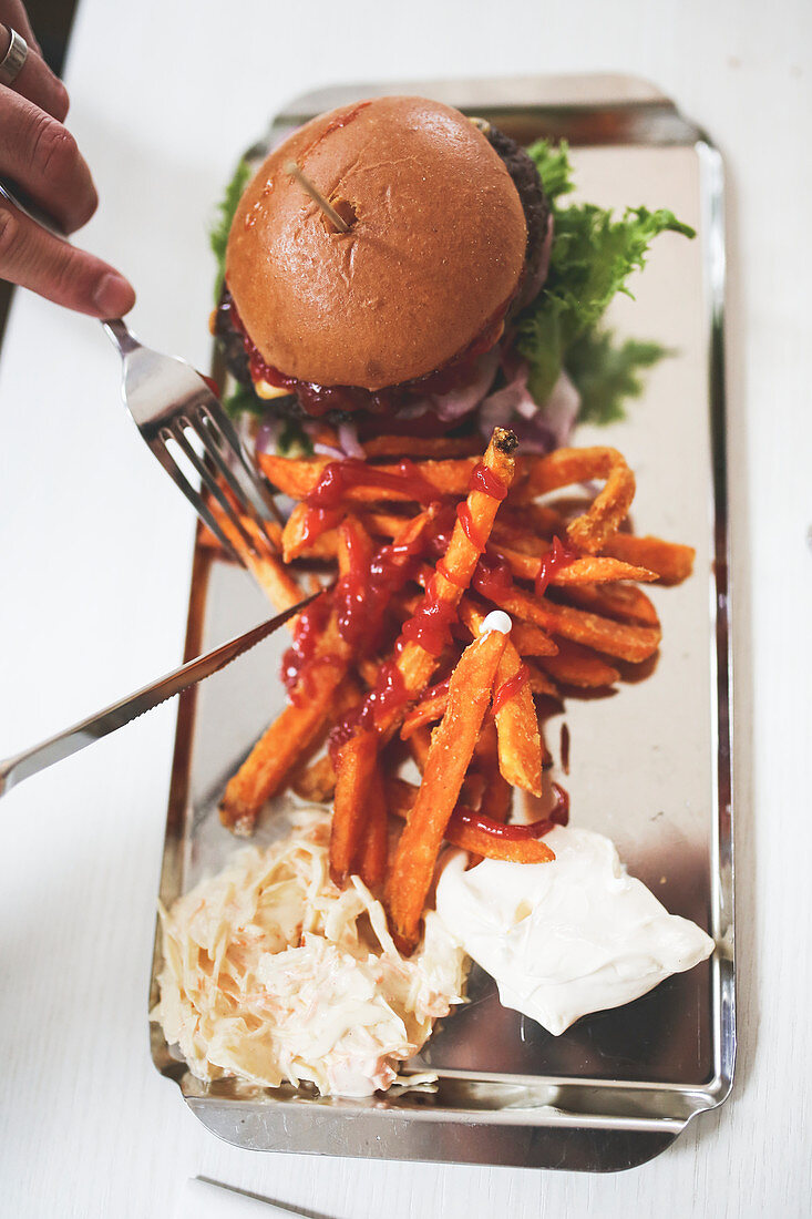 A hamburger with sweet potato fries and coleslaw