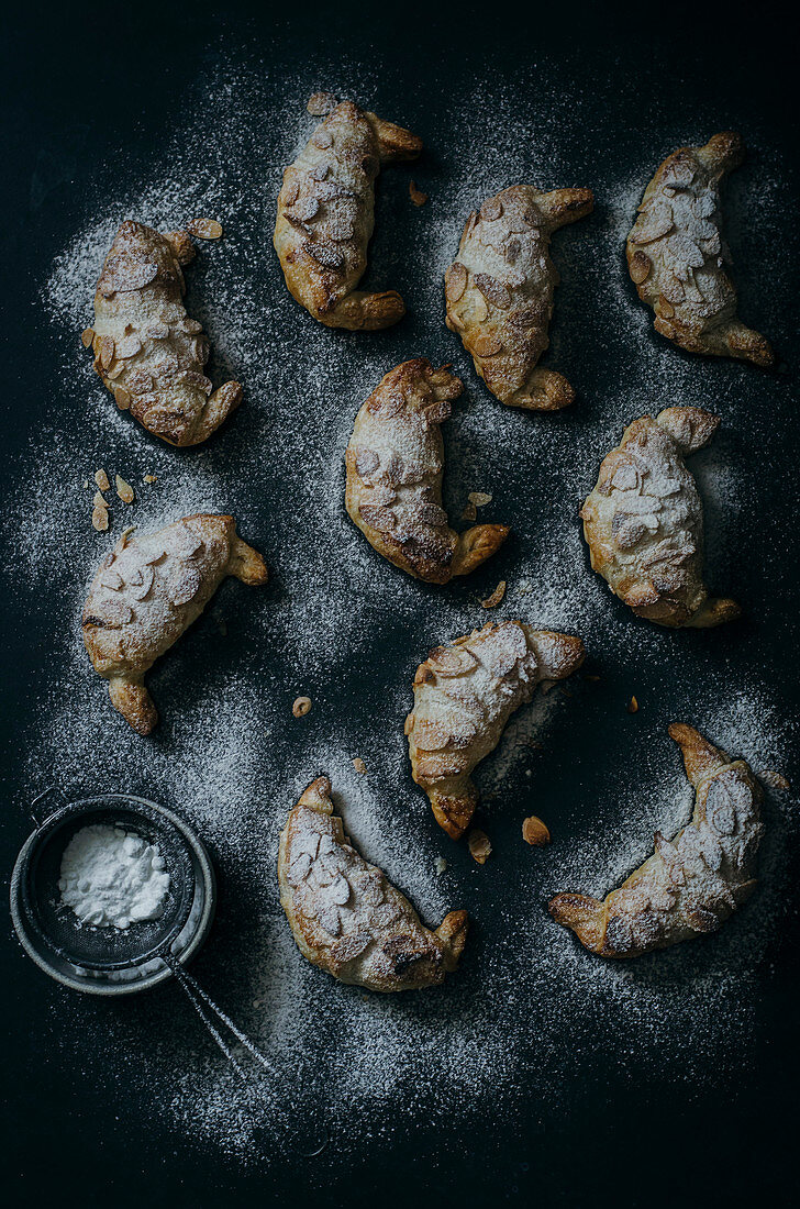 Mandel-Croissants mit Puderzucker auf dunklem Untergrund