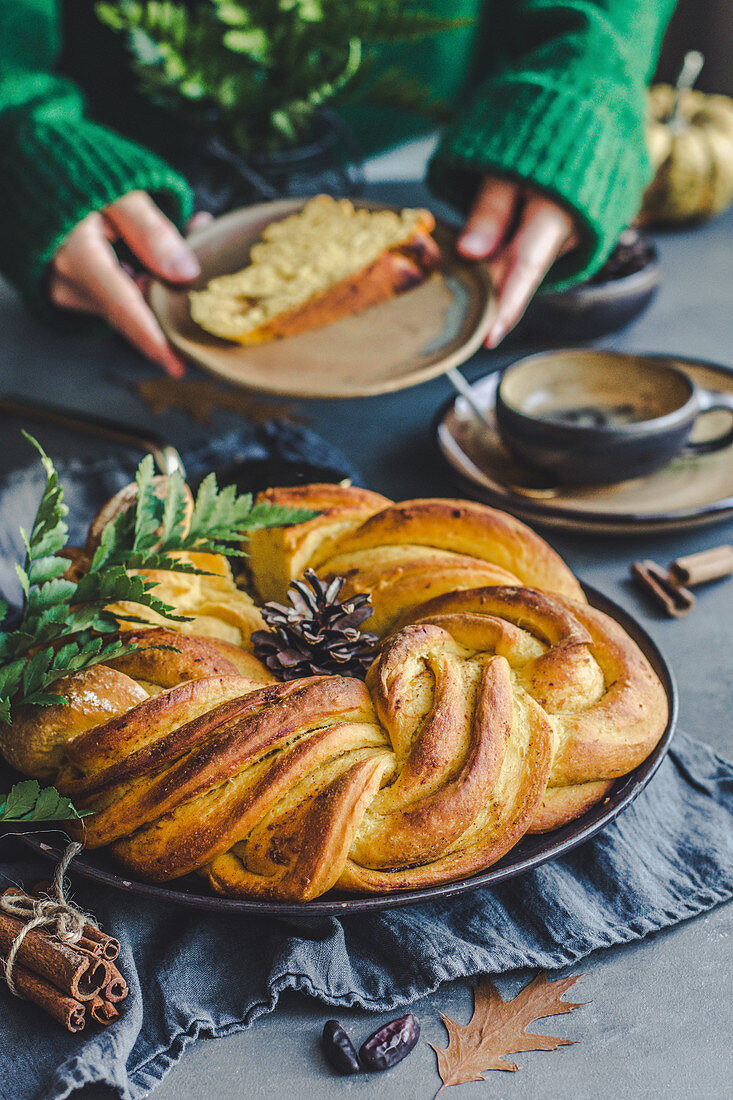 Autumn yeast cinnamon-pumpkin cake in a fancy wreath shape, coffee in the background