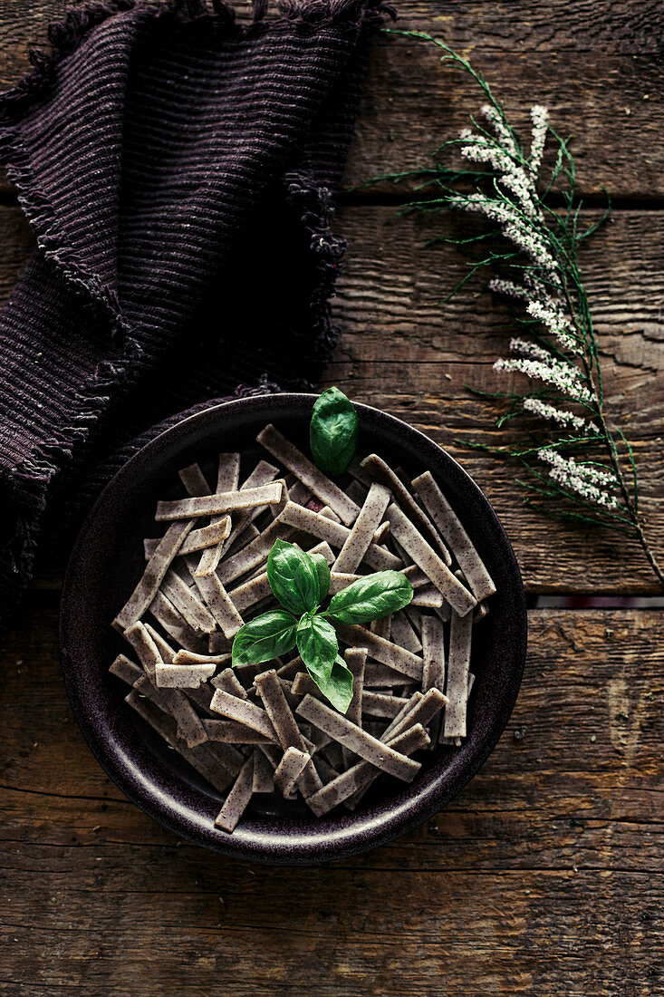 Buckwheat pasta with basil on a wooden table