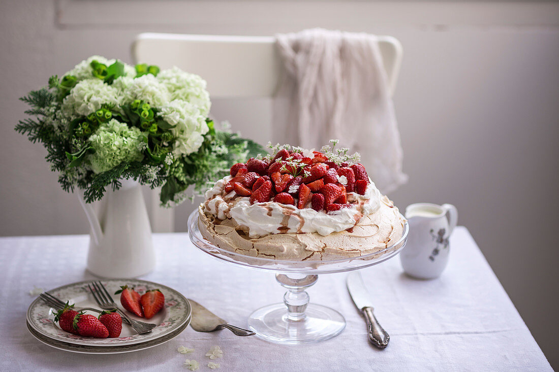 Pavlova cake topped with whipped cream and fresh strawberries