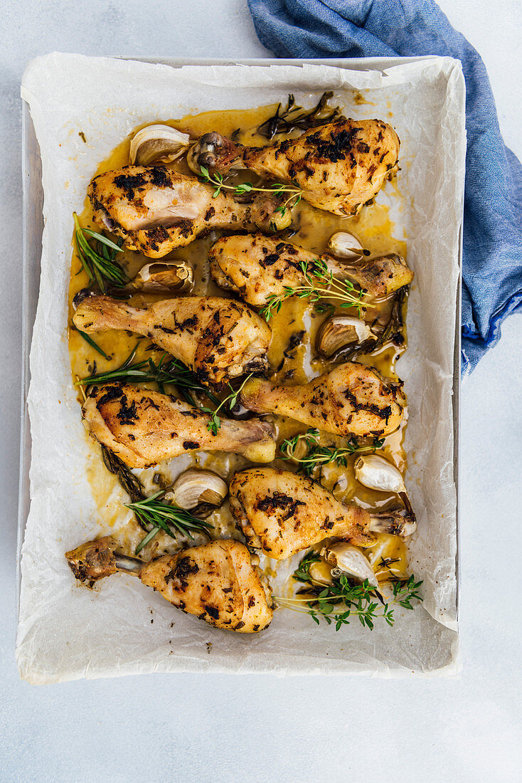 Oven baked chicken legs with herbs and garlic in a baking sheet