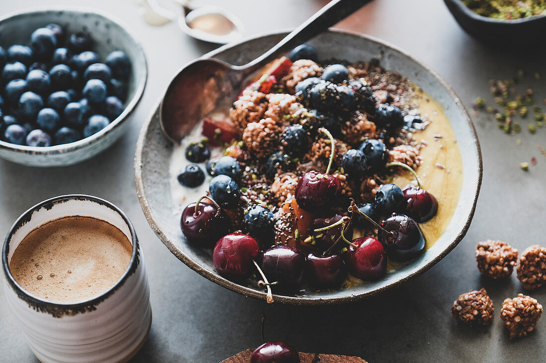 Healthy vegan breakfast set: Quinoa oat granola coconut yogurt bowl with fruit, seeds, nuts, berries and coffee