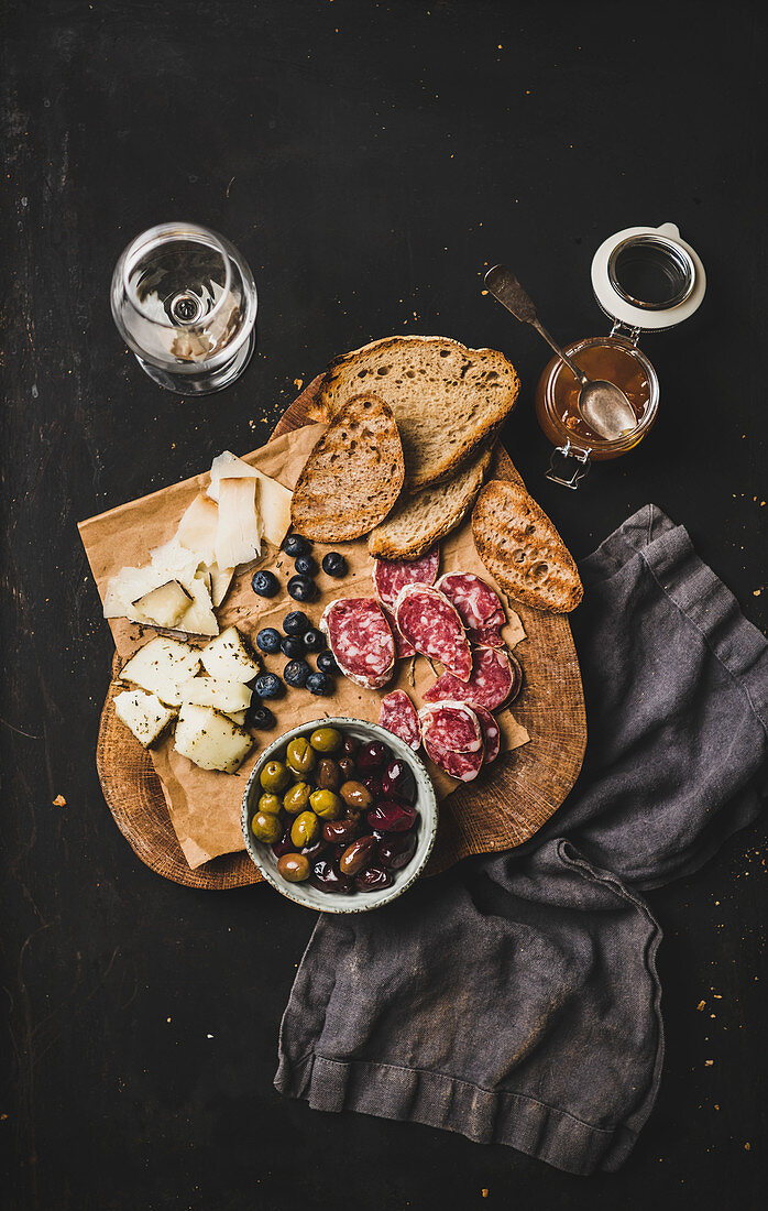 Röstbrot, Käse, Salami und Oliven auf Holzbrett dazu Wein und Marmelade