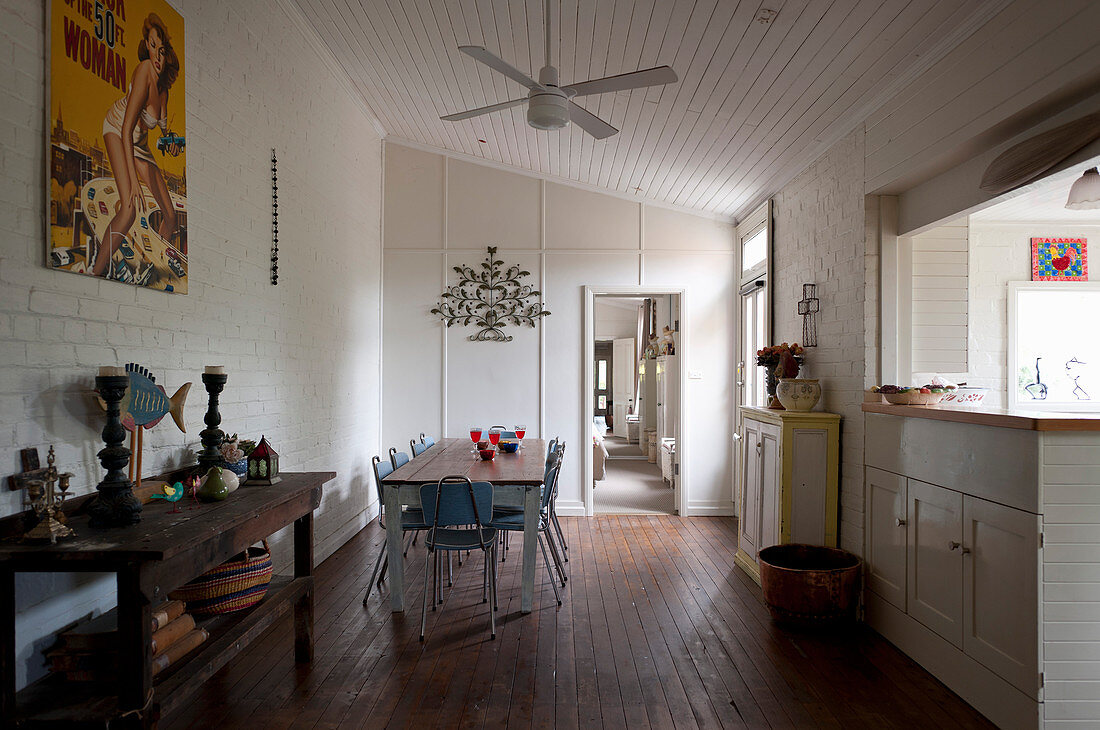 Rustic console table and dining area next to kitchen counter with white-painted brick walls