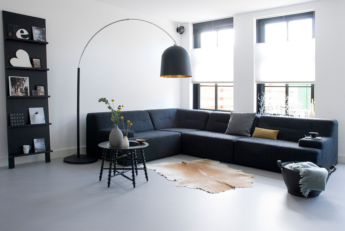 Arc lamp above sofa in minimalist living room in shades of grey