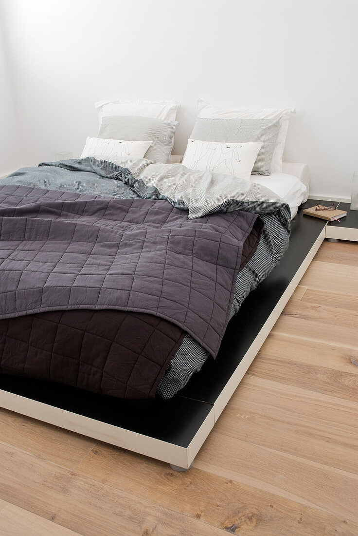 Deep, futon-style bed with layers of covers and quilted bedspread