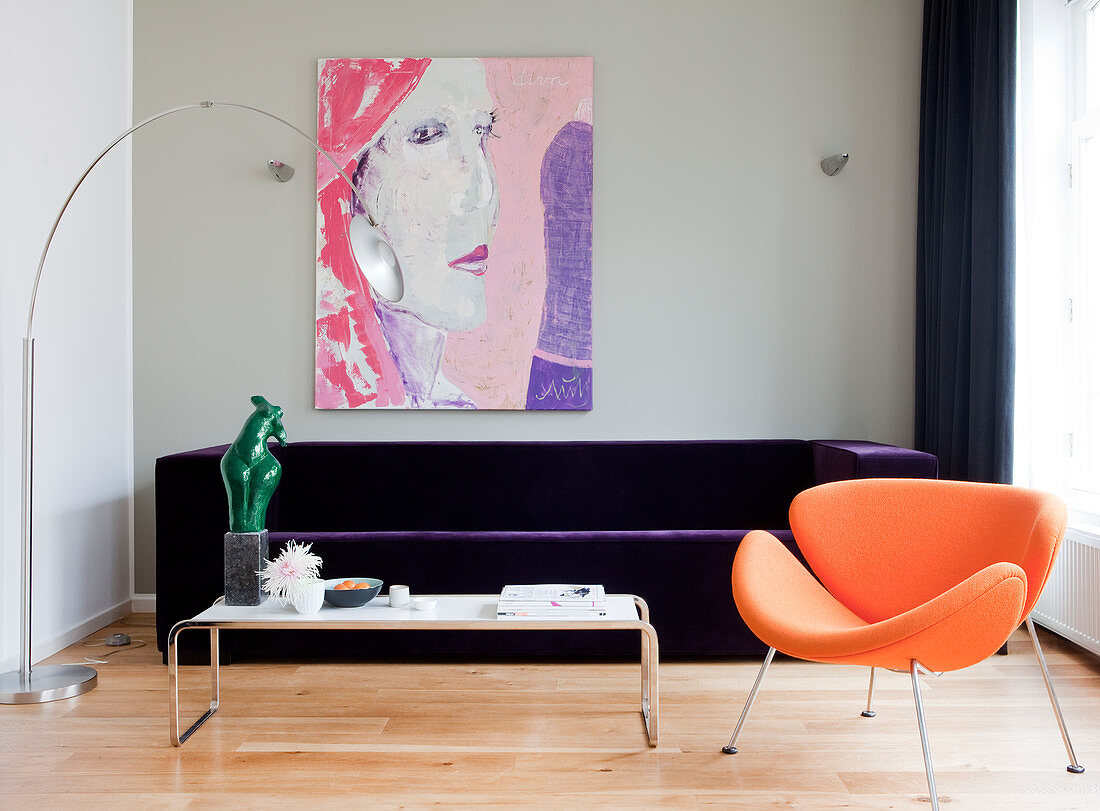 Orange designer armchair in front of purple velvet sofa in living room