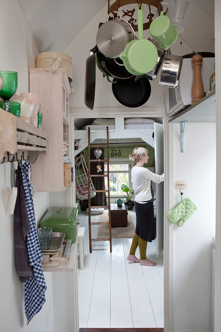 Hängegestell mit Töpfen an der Decke, Frau am Wandschrank