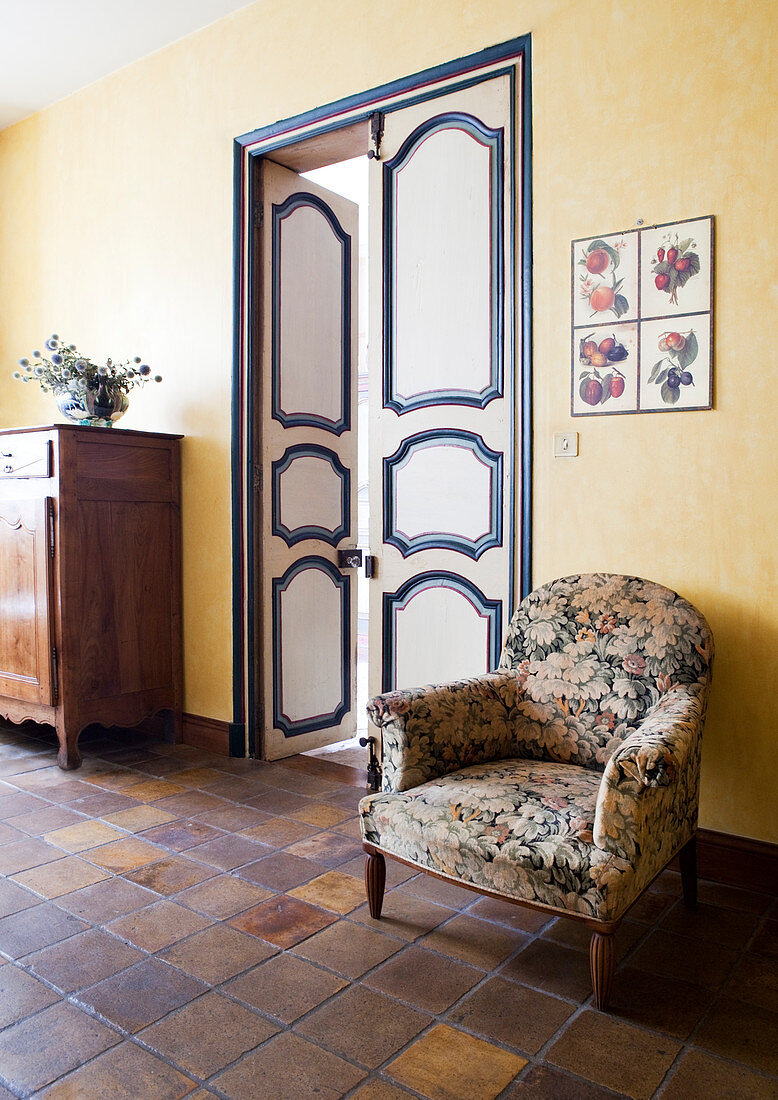 Floral armchair against yellow wall next to painted double doors
