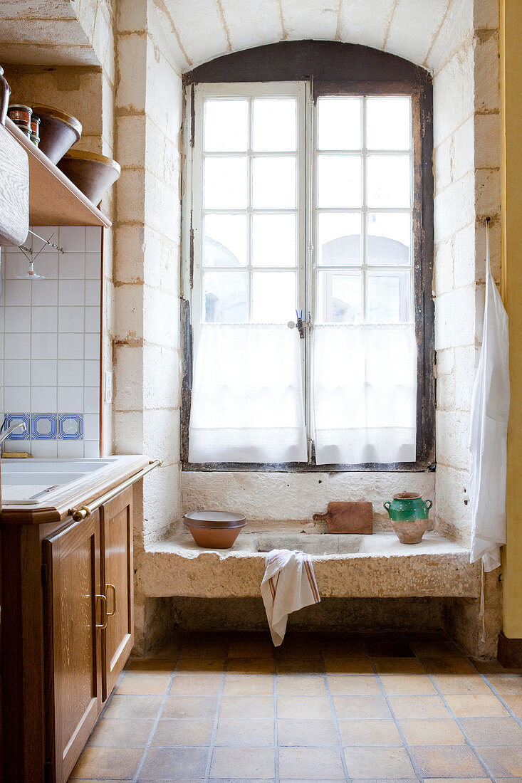 Tall lattice window in rustic country-house kitchen with old stone sink