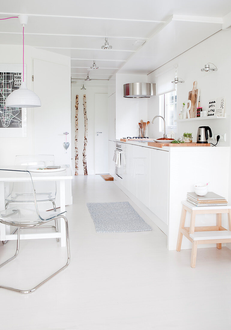 White, open-plan kitchen with white floor and dining area