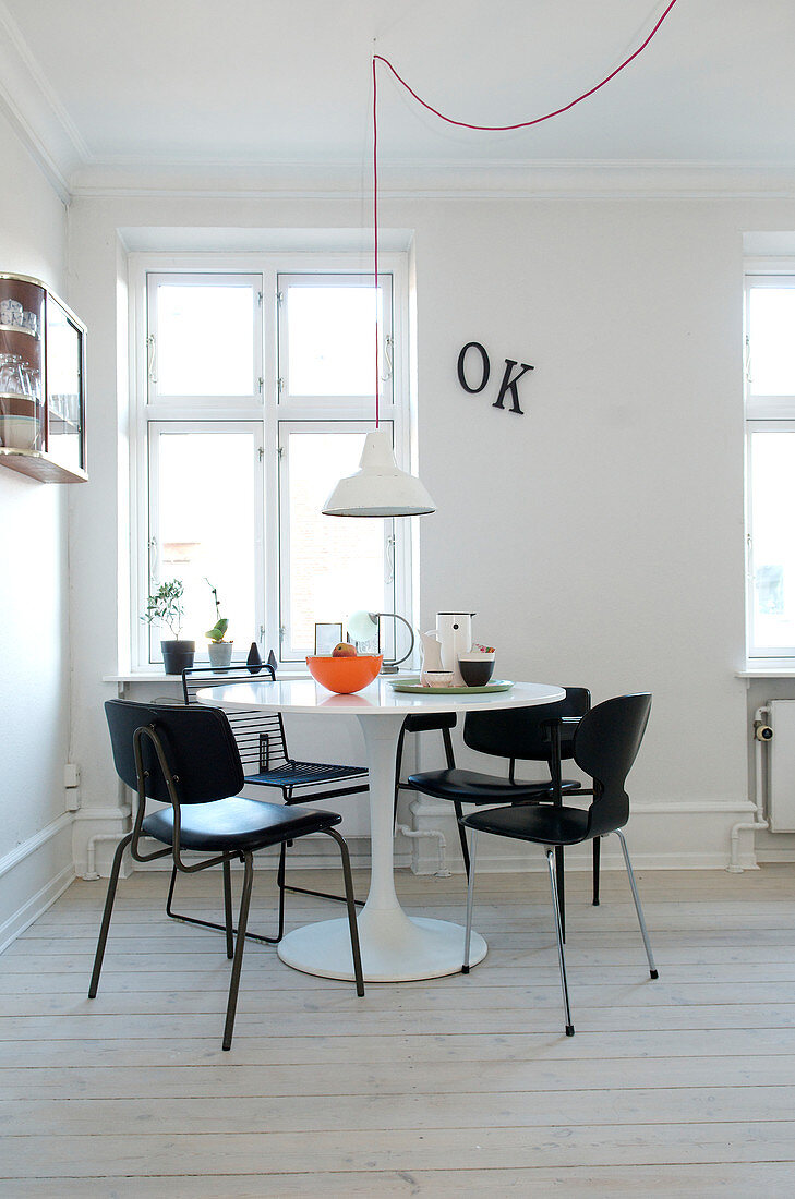 Schwarze Stühle um weißen Designertisch im minimalistischen Esszimmer