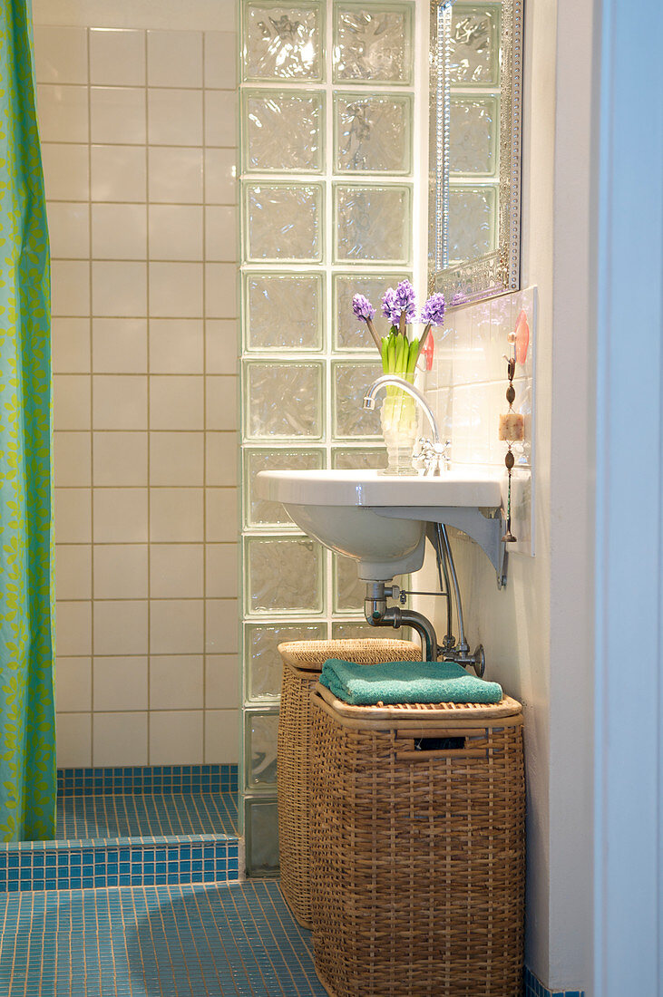 Laundry baskets under a sink in front of the shower with glass block windows