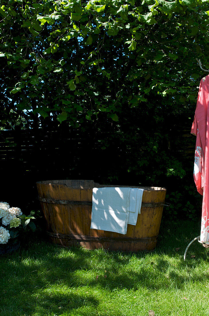 Wooden bathtub on the lawn in the summer garden