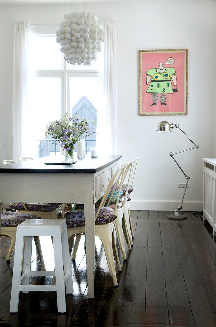 Metal chairs and stools on the old wooden table in the dining room with dark wooden floor