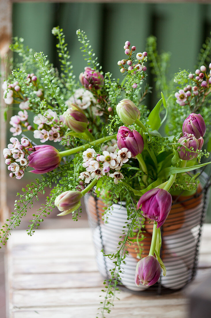 Blumenstrauß mit Tulpen, Hirtentäschel und Australischer Wachsblume im Metallkorb mit Eiern