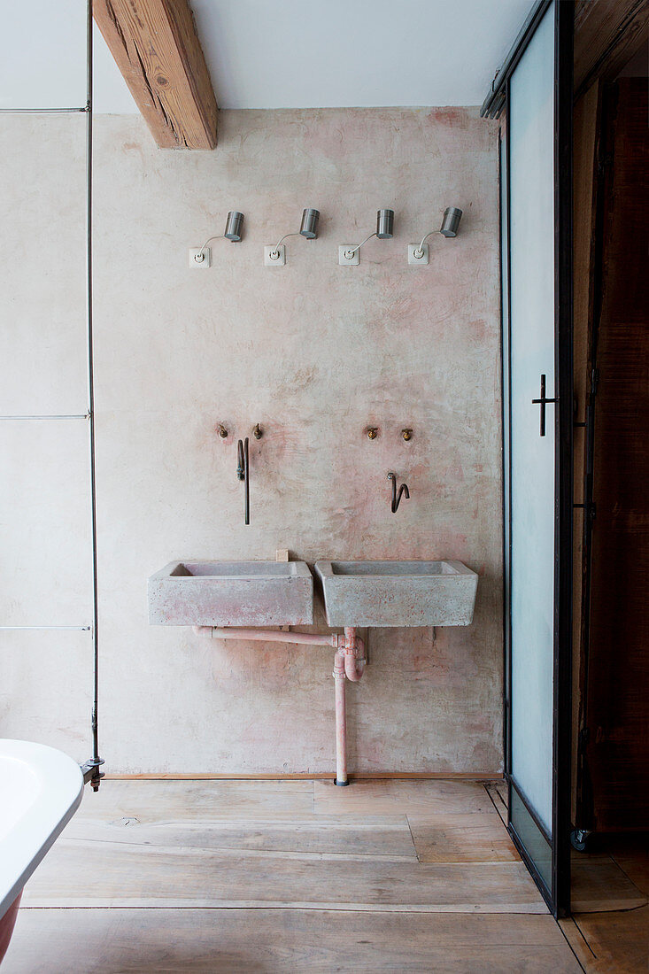 Twin concrete sinks with vintage, wall-mounted tap fittings