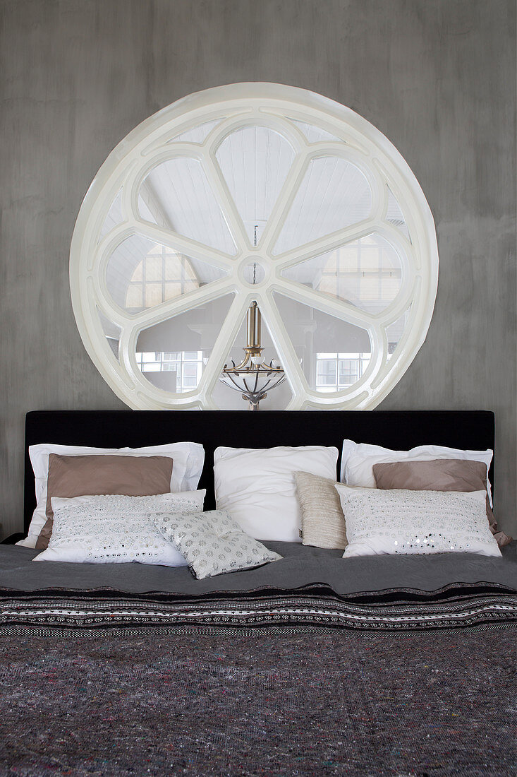 Bed below rose window in grey wall