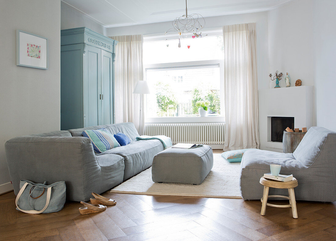 Modern grey sofa set in living room with large window and parquet floor