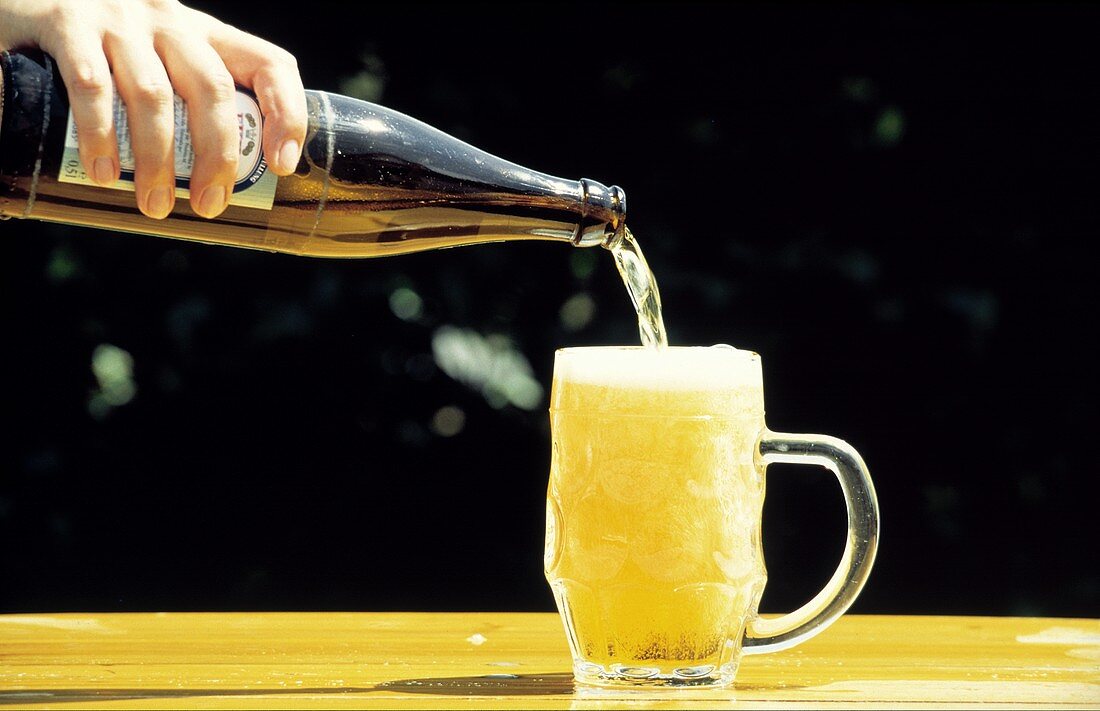 Bier wird aus Flasche in einen Krug Bier gegossen