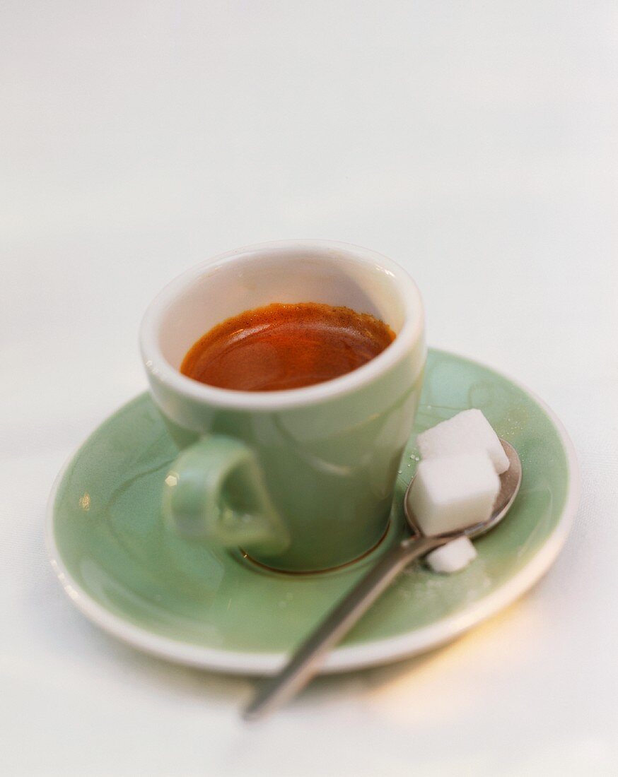 Espresso in grüner Tasse mit Löffel & Würfelzucker