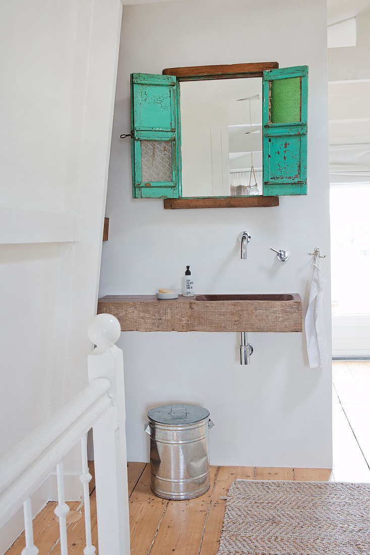 Turquoise decorative window with mirror above the stone washbasin