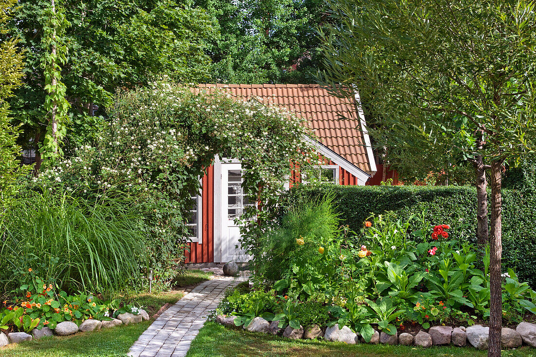 Gartenbeete und Rankbogen vor Schwedenhäuschen