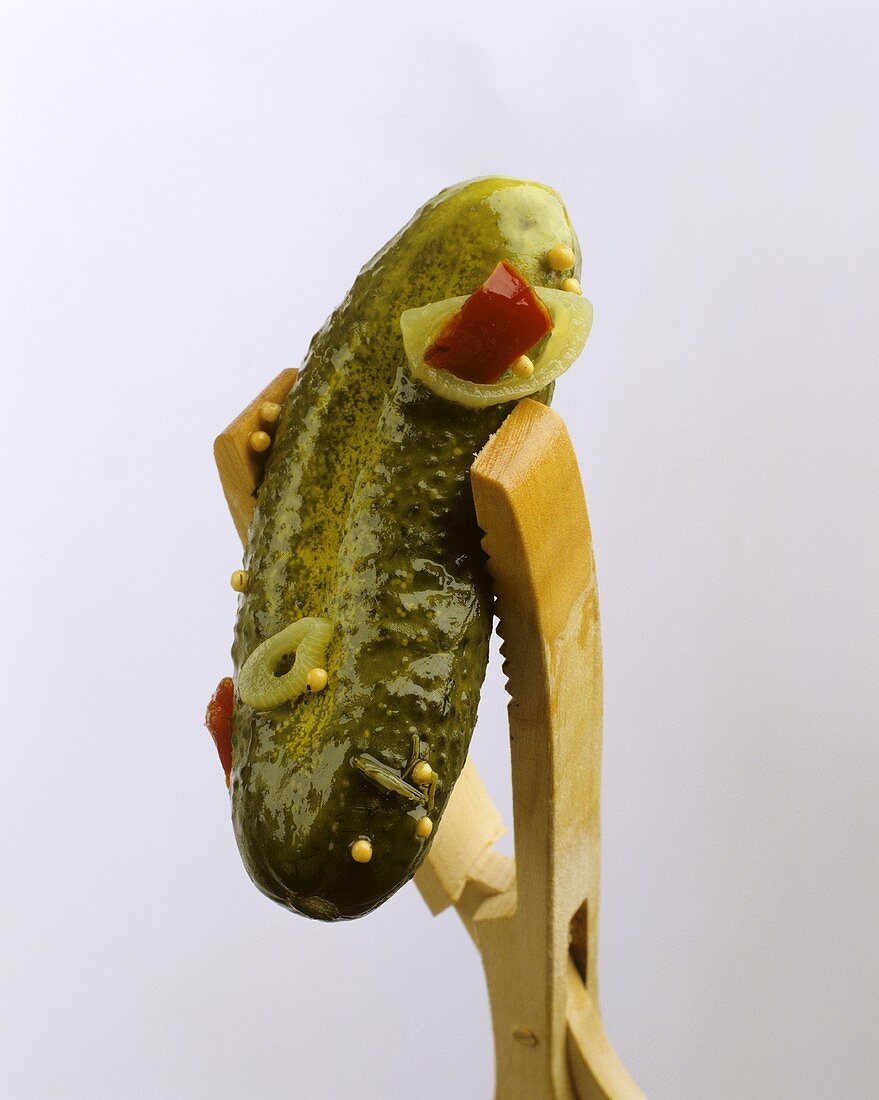 Wooden tongs holding a pickled gherkin