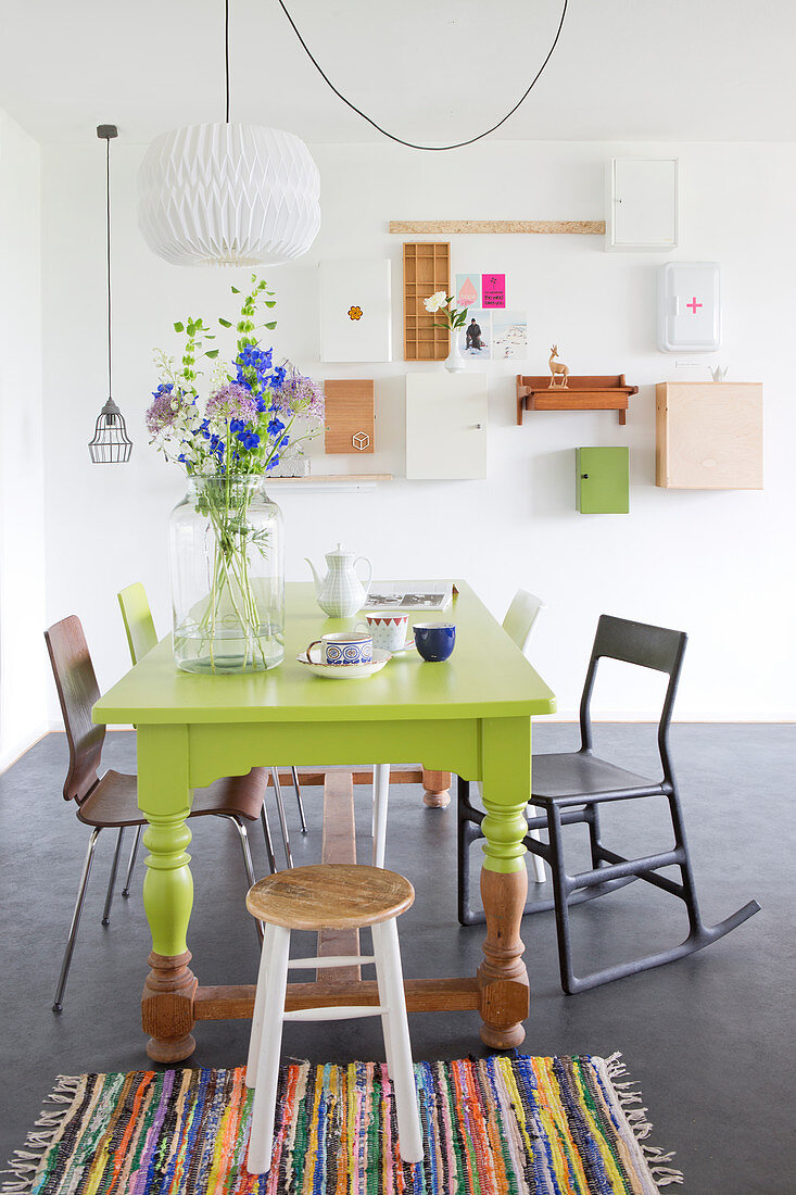 Green-painted dining table and various chairs in dining area