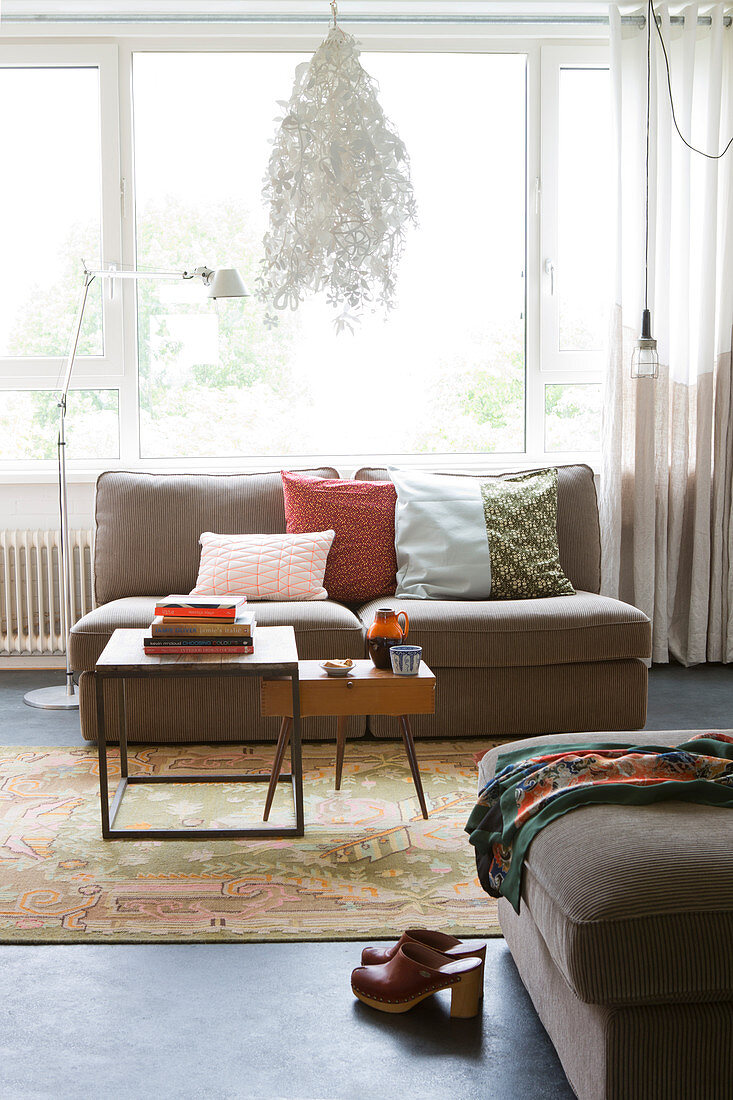 Polstersofa mit Kissen und Retro Couchtisch vor Fenster im Wohnzimmer