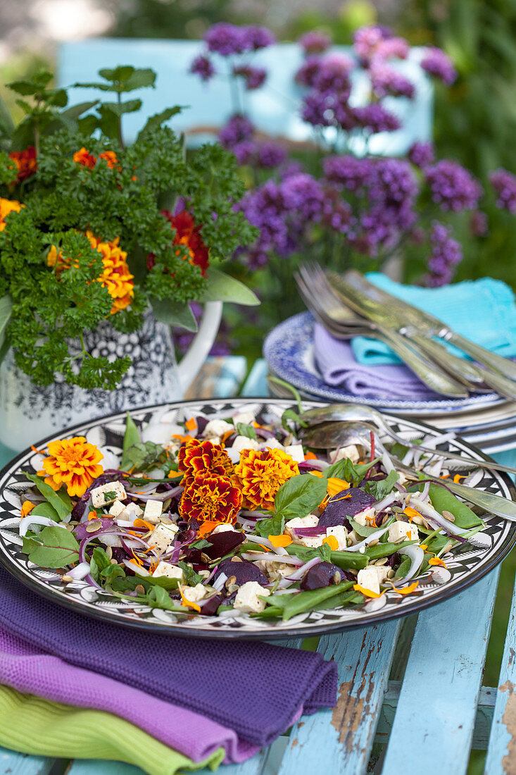 Salad with French marigold petals and bouquet of parsley on garden table