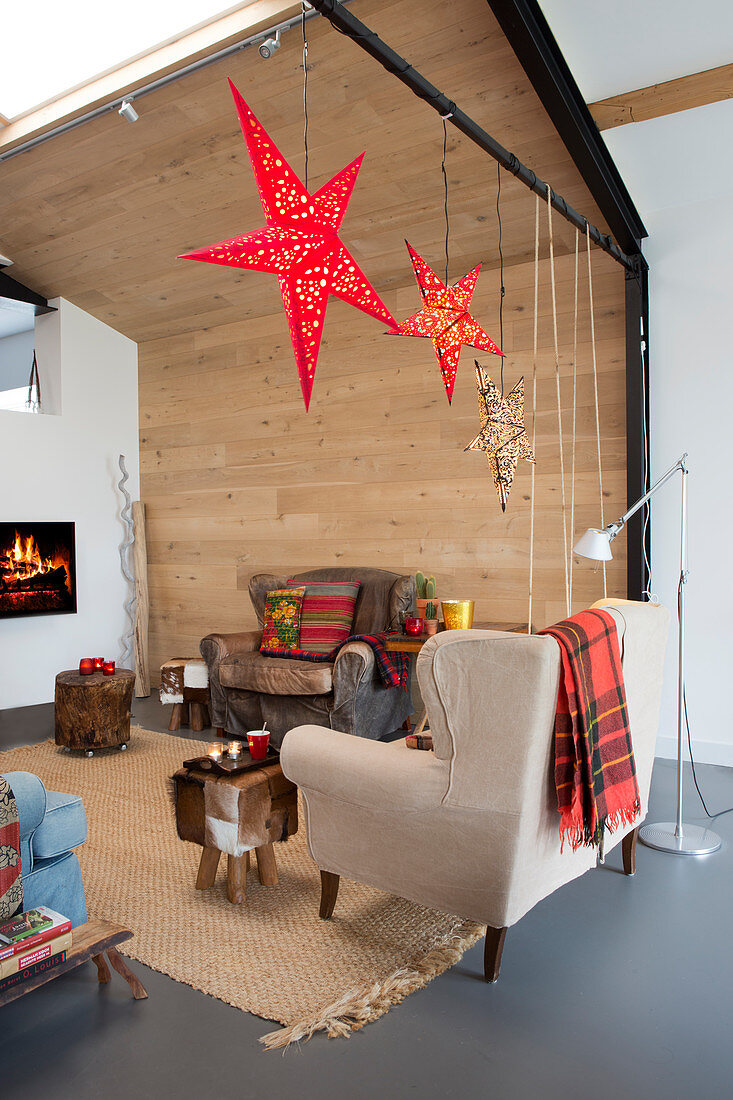 Gemütliche Sessel vor Kamin und Weihnachtsdekoration im Wohnzimmer mit Holzverkleidung