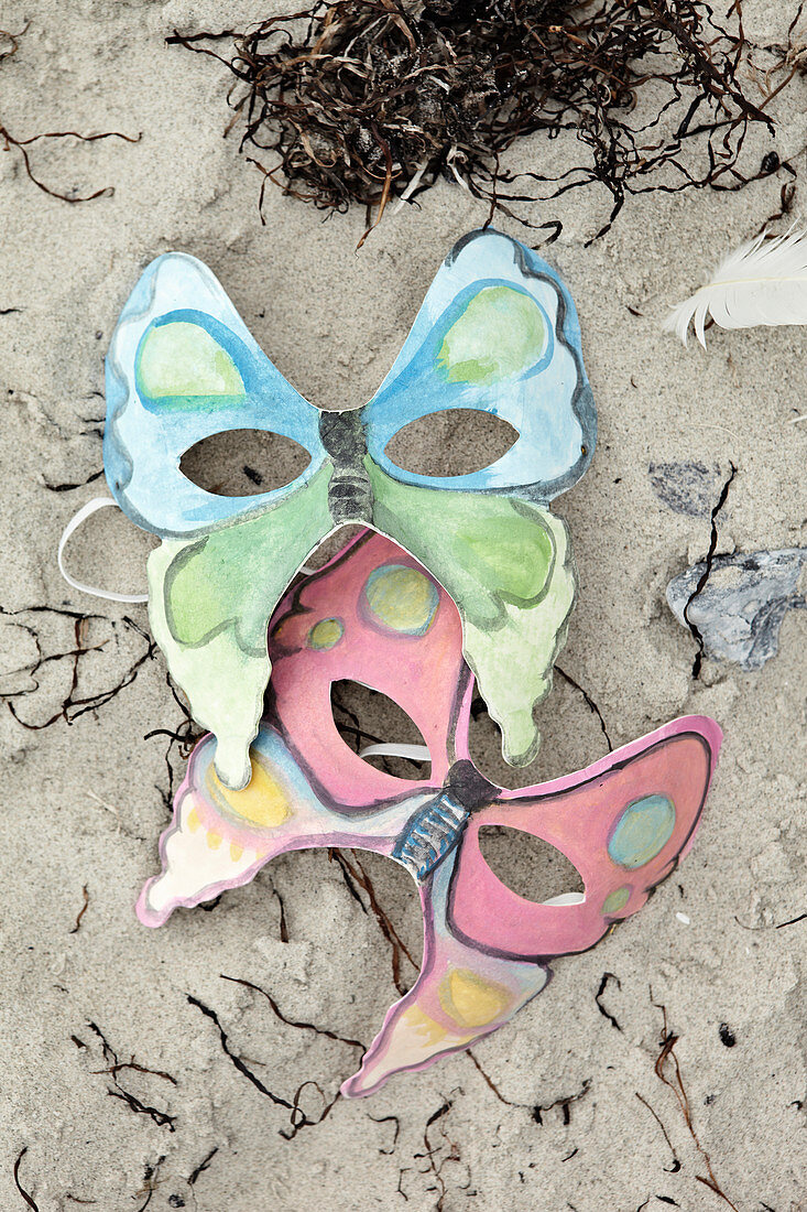Homemade masks with butterfly motifs in the sand