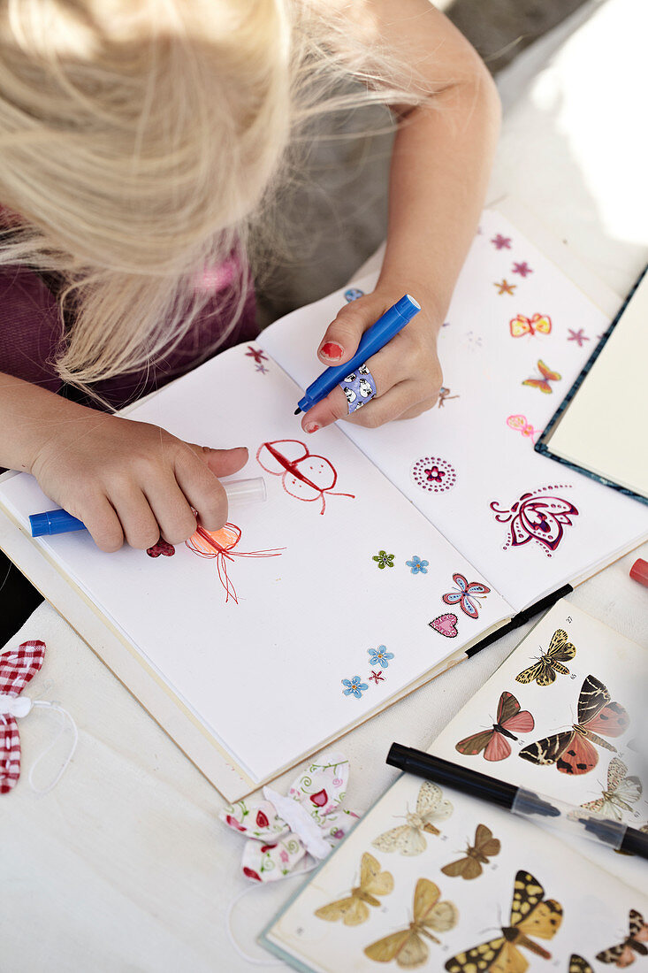 Girl paints butterflies in a notebook