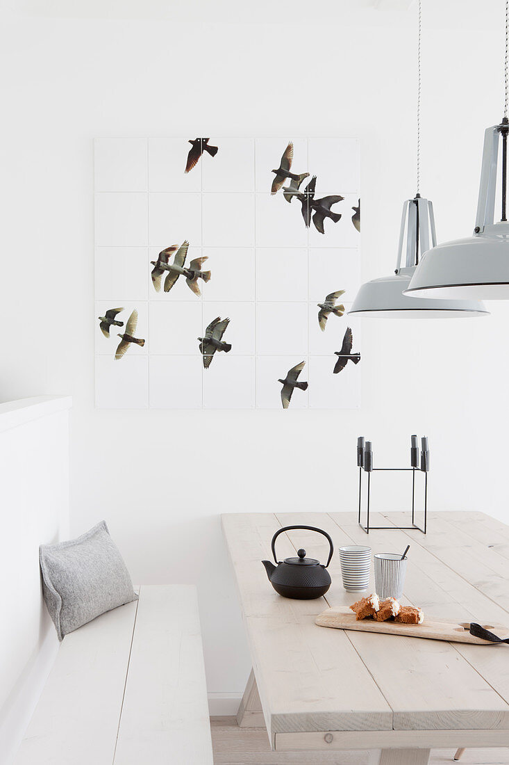 Wanddeko mit Vogelmotiv über dem hellen Holztisch