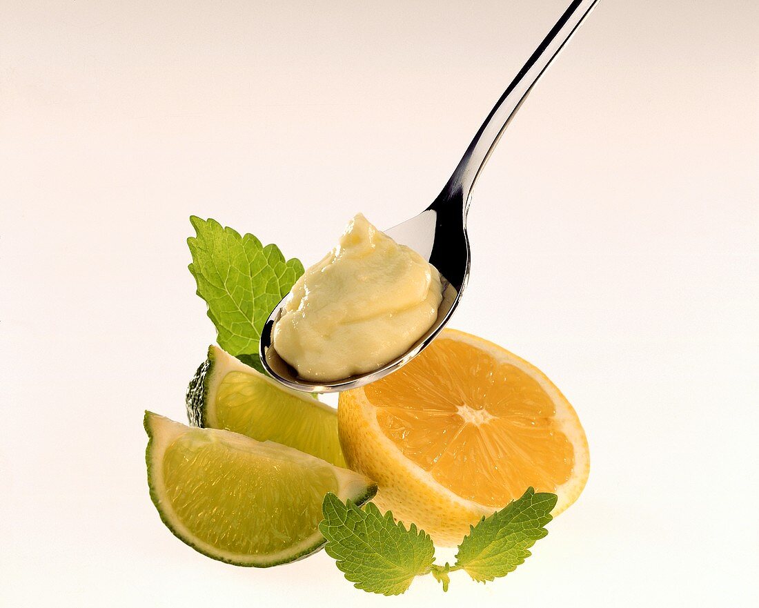 Lemon mayonnaise on spoon, decoration: lemon, limes, mint