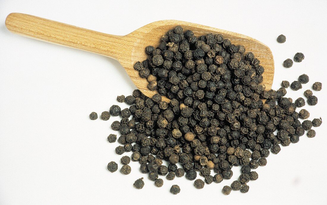 Black Peppercorns Spilling out of a Wooden Scoop