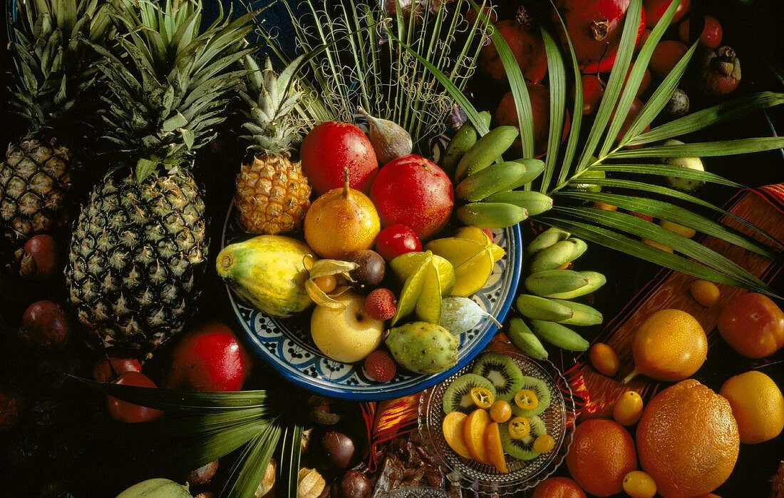 Viele tropische Früchte in Schalen & auf Tisch verteilt