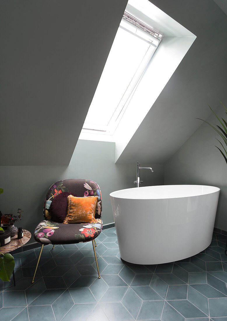 A free-standing bathtub and chair in an attic bathroom