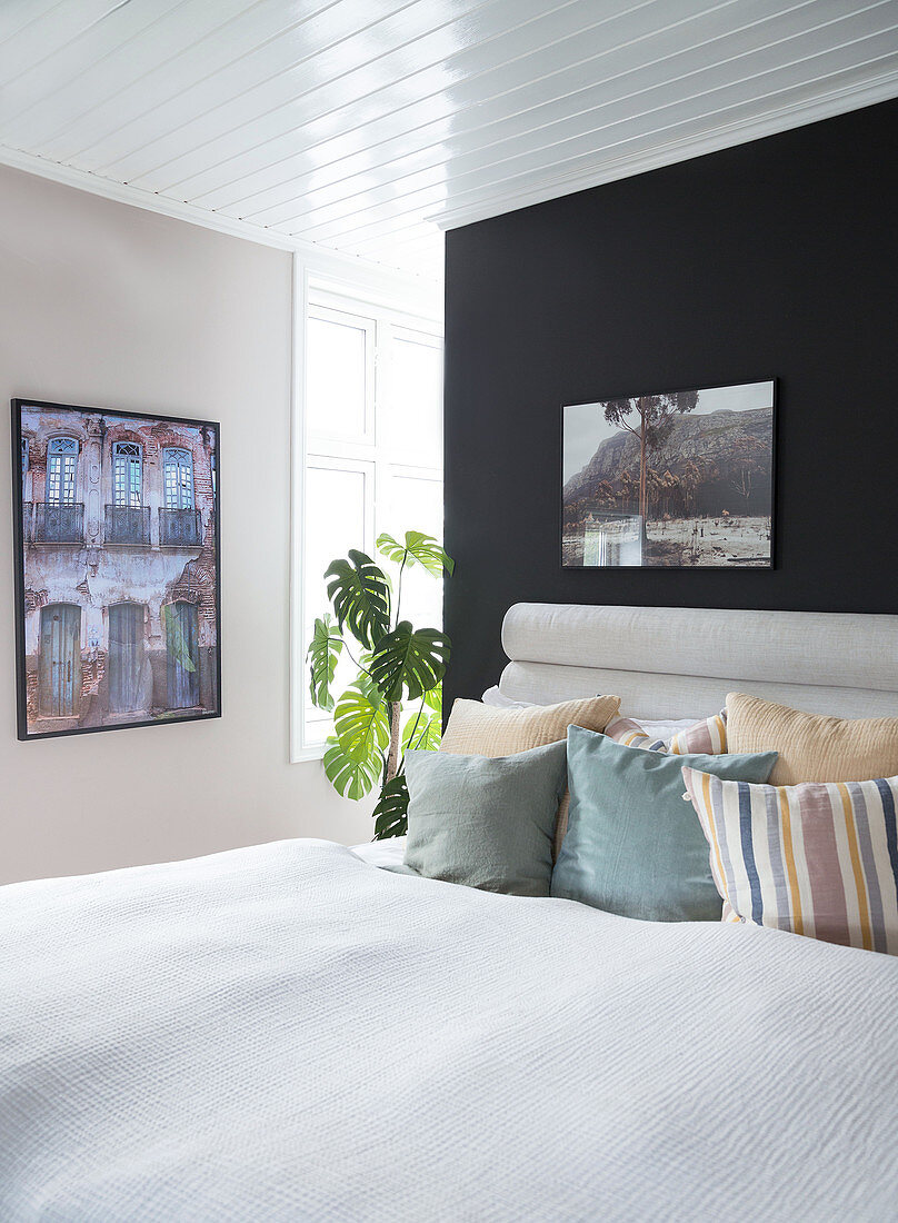 A bed with pillows in front of a black wall