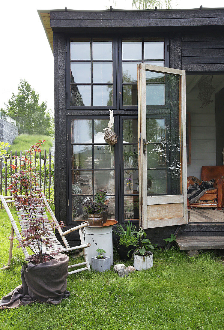 A bamboo chair in front of a glass house made from recycled materials