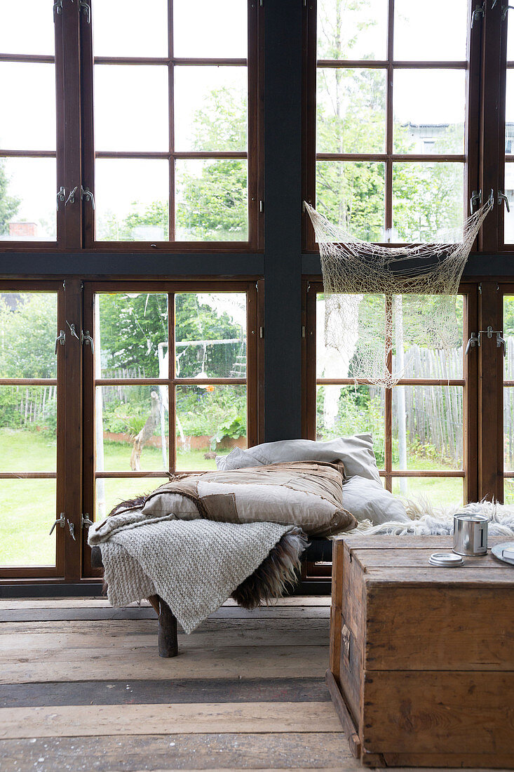 Wooden chest and day bed with blankets in the glass house