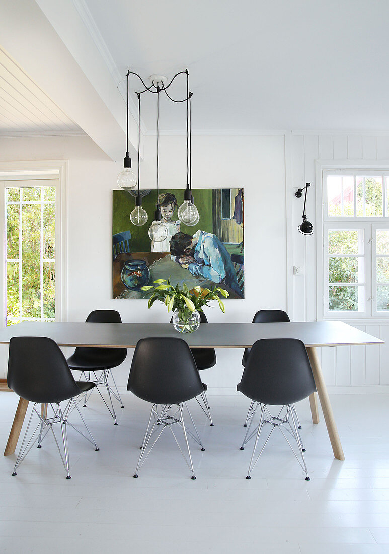 Dining table with black classic chairs, pendant light above in open living area