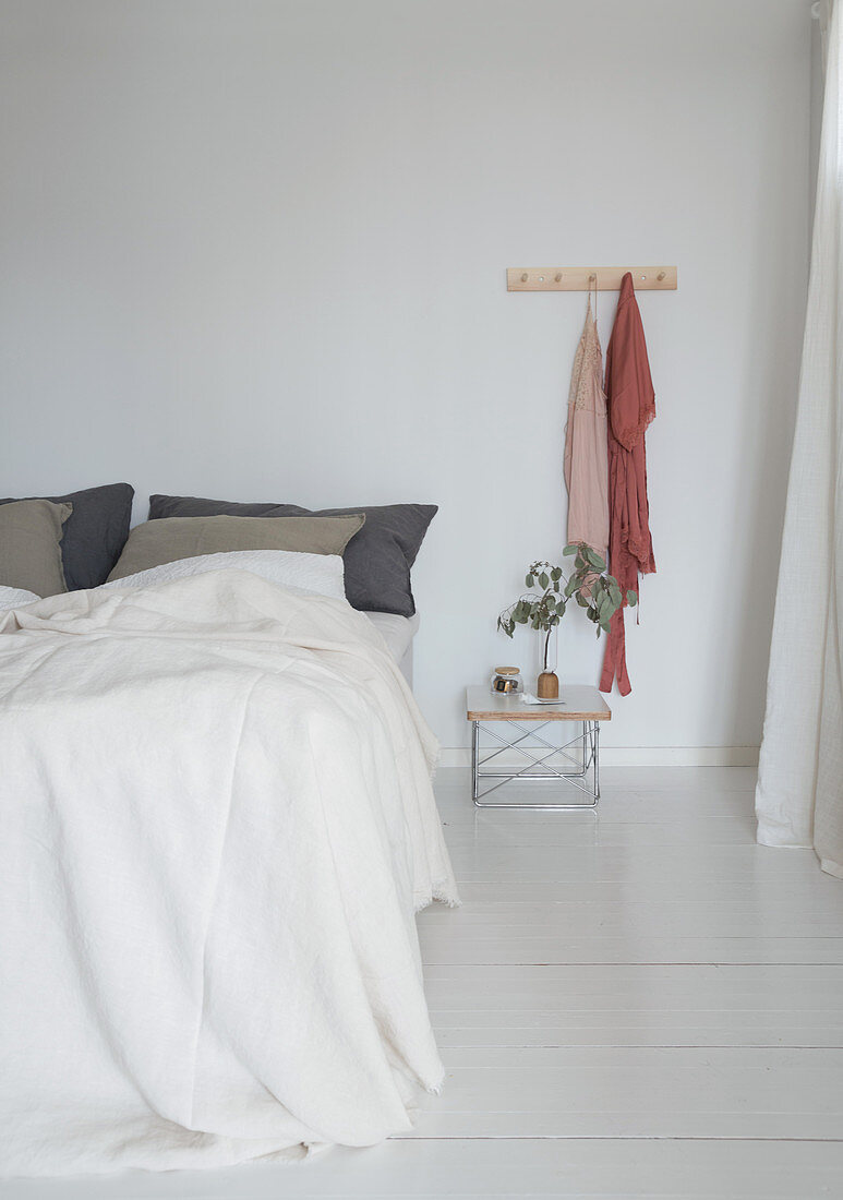 Double bed in minimalist bedroom with white floorboards