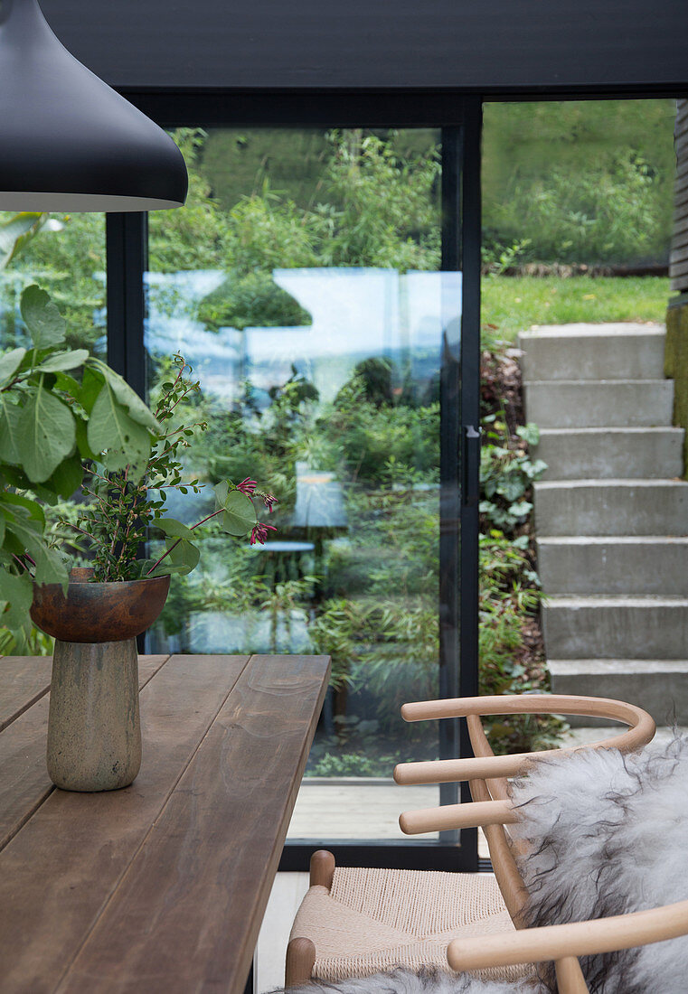 Self-made wooden dining table with classic chairs in the winter garden